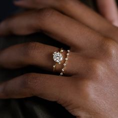 a woman's hand with two gold rings on her left and the other hand holding an engagement ring