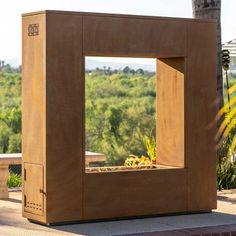 an outdoor planter made out of wood with plants in the center and trees in the background