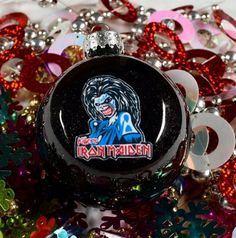 a glass ornament with the logo of iron maiden on it surrounded by christmas decorations