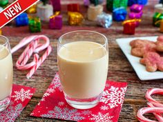 two glasses filled with milk sitting on top of a table next to candy canes