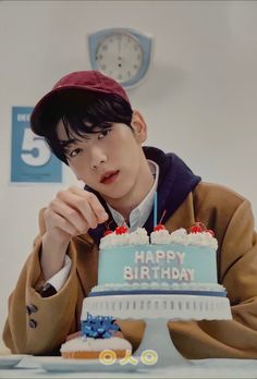 a young man sitting at a table in front of a birthday cake