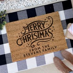 a merry christmas door mat with the words from the stevens family on it next to a person's feet