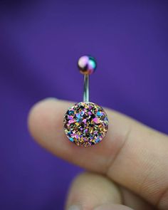 a person is holding a tiny piercing with colorful glitters on it's end