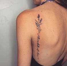 the back of a woman's shoulder with flowers and words tattooed on her left side