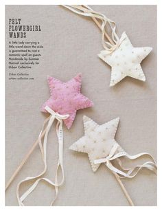 three white and pink stars are hanging from strings on a gray background with the words felt flowergirl wands written below them