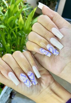 two hands with white and purple nail polishes