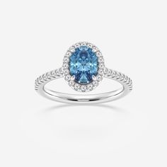 a blue diamond ring with white diamonds on the band and an oval shaped center stone