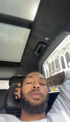 a man laying in the back seat of a car with his head up and eyes closed