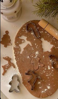 cookie cutters and gingerbread cookies on a white plate with christmas decorations in the background