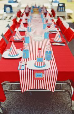 a long table set up with red and white striped cloths, plates and napkins