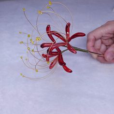 a person is working on some kind of flower decoration with wire and bead work