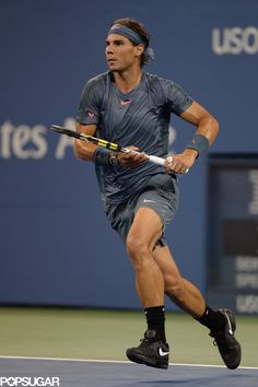 a male tennis player is running with his racket in one hand and headband in the other