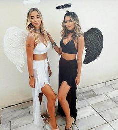 two women standing next to each other in front of a wall with angel wings on it