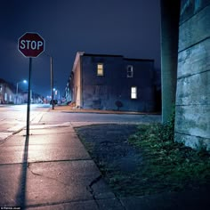 a stop sign on the corner of an empty street at night with no one around it