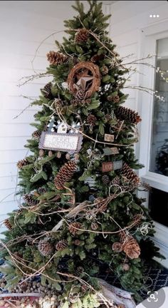 a decorated christmas tree with pine cones and other decorations on the top, in front of a house