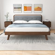 a bed sitting on top of a wooden floor next to two framed pictures above it