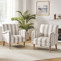 a living room with two striped chairs and a potted plant in front of the fireplace