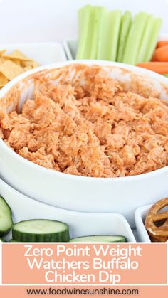 a white bowl filled with chicken dip surrounded by celery, carrots and cucumbers