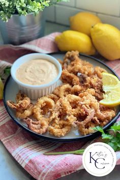 fried onion rings with dipping sauce on a plate next to lemons and parsley