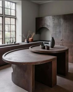 an oval table in the middle of a kitchen with two vases on top of it