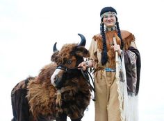 a woman in native clothing standing next to a yak