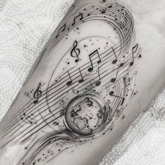 a black and white photo of music notes on the arm with a globe in it