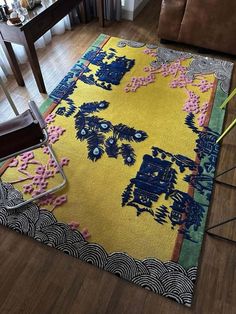 a yellow rug with blue and pink designs on it in the middle of a living room