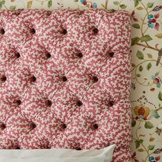 an upholstered headboard with flowers and leaves on the wall next to a pillow