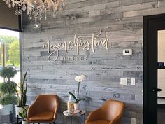 two brown chairs sitting in front of a wooden wall