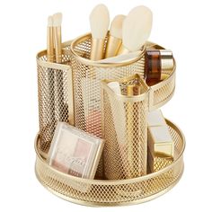 a gold metal container with makeup brushes and other items in it