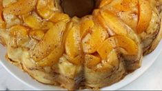 a bundt cake on a white plate topped with sliced peaches