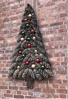 a christmas tree made out of pine cones on a brick wall