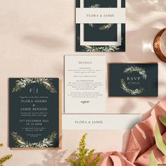 the wedding stationery is laid out with greenery