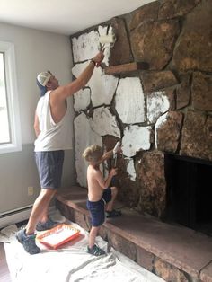 a man and boy painting a stone fireplace