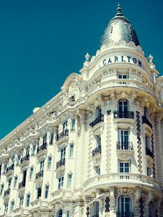 a tall white building with a clock on the top of it's face in front of a blue sky