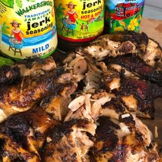 chicken and other foods on a cutting board next to jars of jerk seasoning