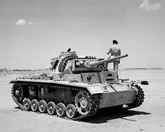 a man standing on top of a tank in the desert