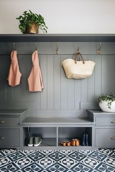 an entryway with gray painted wood paneling and coat racks