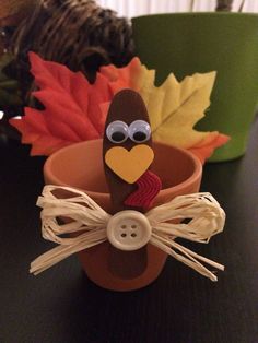 a cup that has a turkey in it and some leaves on the table next to it