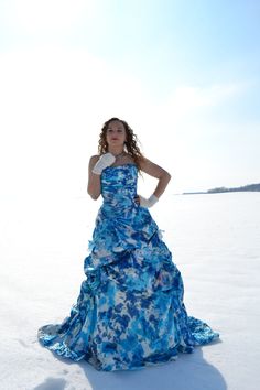 a woman in a blue and white dress standing in the snow with her hands on her hips