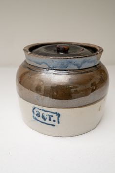 a brown and white pot with blue writing on it's lid sitting on a table