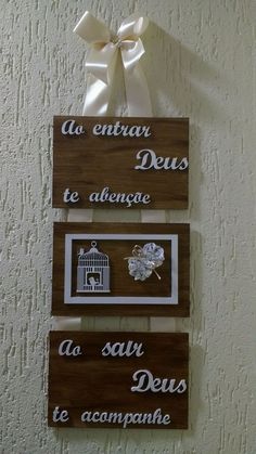 three wooden signs hanging from the side of a wall next to a white bow and ribbon