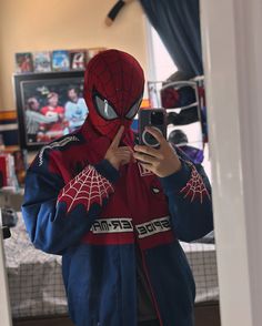 a person wearing a spider man costume taking a selfie with their phone in front of him