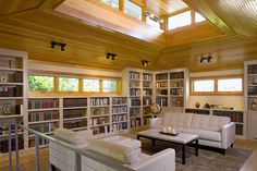 a living room filled with lots of furniture and bookshelves covered in wooden beams