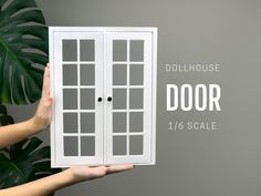 a person holding up a door with the words dollhouse on it's side