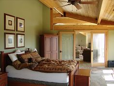 a large bed sitting under a wooden ceiling in a bedroom next to a doorway with glass doors