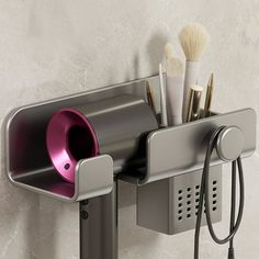 a cup holder is attached to the side of a wall with makeup brushes in it