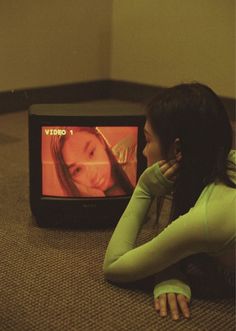 a woman laying on the floor in front of a television with her hand on her face