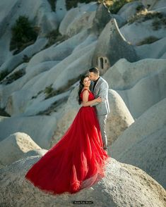 a man and woman standing on top of a rock