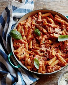 a pan filled with pasta and sauce on top of a wooden table